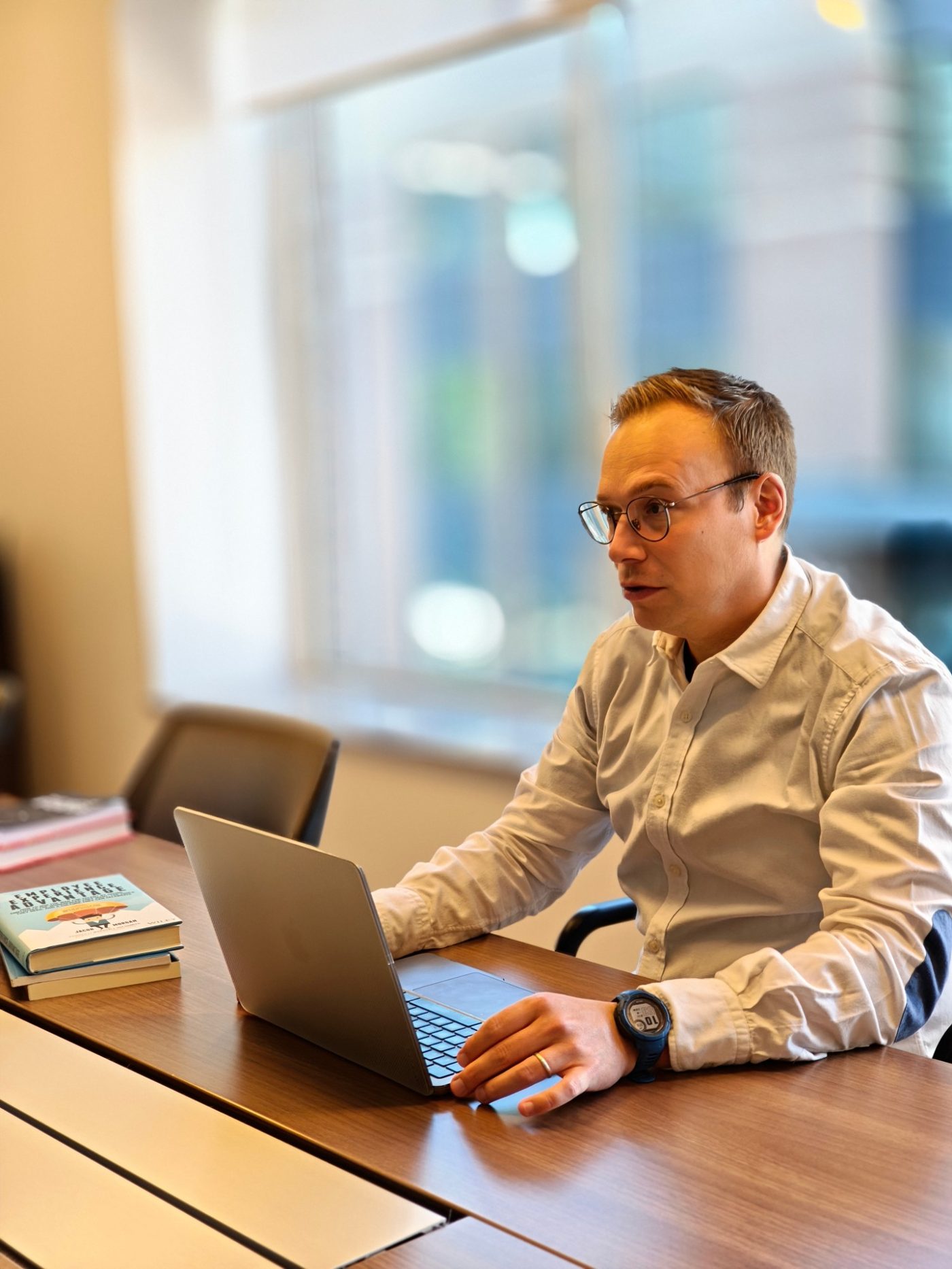 Cristijn Cambré aan de telefoon, naast een stapel boeken over employee experience